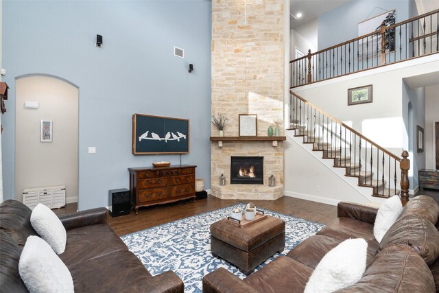 living room with arched walkways, a high ceiling, wood finished floors, and stairway