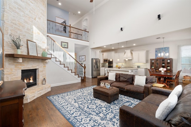 living room with stairway, a high ceiling, baseboards, a fireplace, and dark wood-style flooring