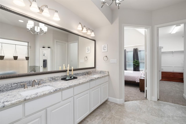 full bath featuring baseboards, a notable chandelier, a sink, and double vanity