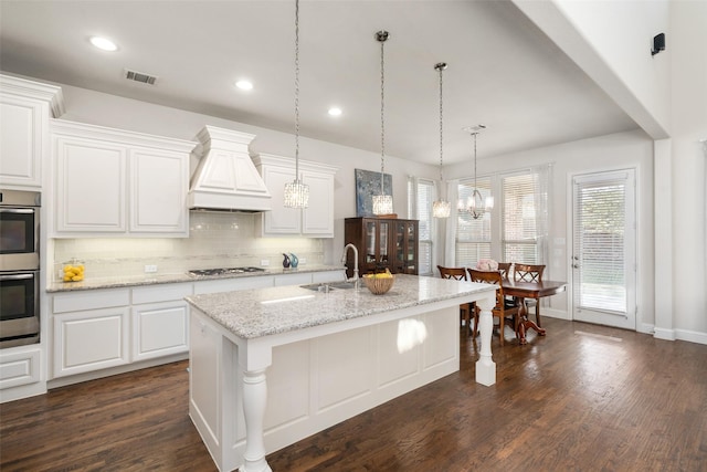 kitchen with visible vents, a sink, decorative backsplash, appliances with stainless steel finishes, and custom exhaust hood