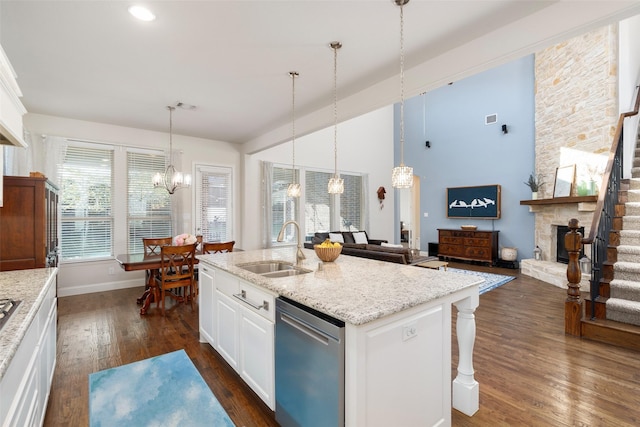 kitchen with white cabinets, dark wood-style floors, a sink, a notable chandelier, and light stone countertops