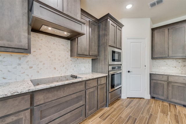 6517 Harwich Dr, Mesquite, TX 75181 - kitchen with stainless steel oven, dark brown cabinets, visible vents, premium range hood, and black electric cooktop