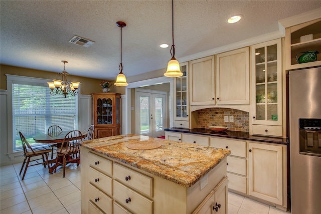 kitchen featuring an inviting chandelier, stainless steel fridge, a center island, visible vents, and light brown cabinetry