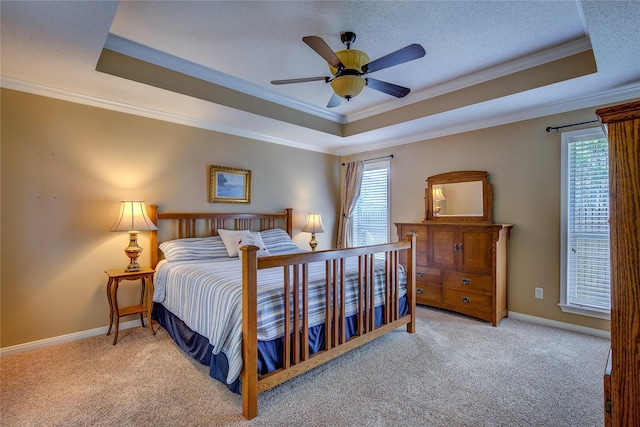 bedroom featuring ornamental molding, a tray ceiling, multiple windows, and carpet flooring