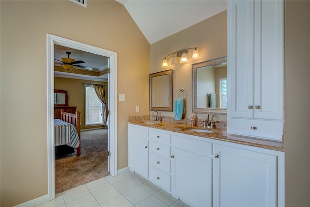 ensuite bathroom featuring tile patterned floors, ensuite bath, vaulted ceiling, and a sink