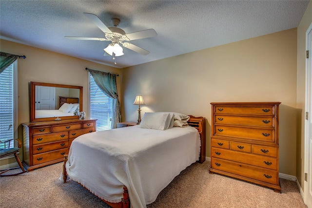 bedroom with light colored carpet, a ceiling fan, and a textured ceiling