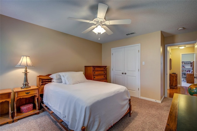 bedroom with a closet, baseboards, carpet flooring, visible vents, and ceiling fan