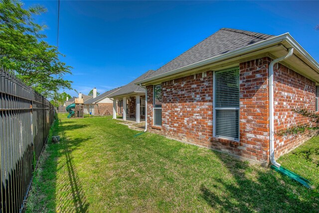 exterior space with a yard, brick siding, a fenced backyard, and a playground