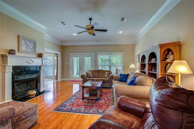 living area with a textured ceiling, wood finished floors, ceiling fan, and visible vents