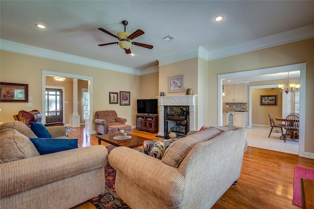 living area featuring crown molding, visible vents, recessed lighting, and ceiling fan with notable chandelier