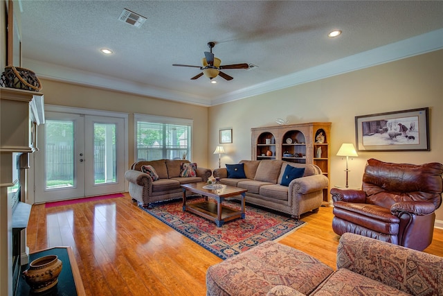 living room featuring a textured ceiling, french doors, visible vents, and light wood-style floors