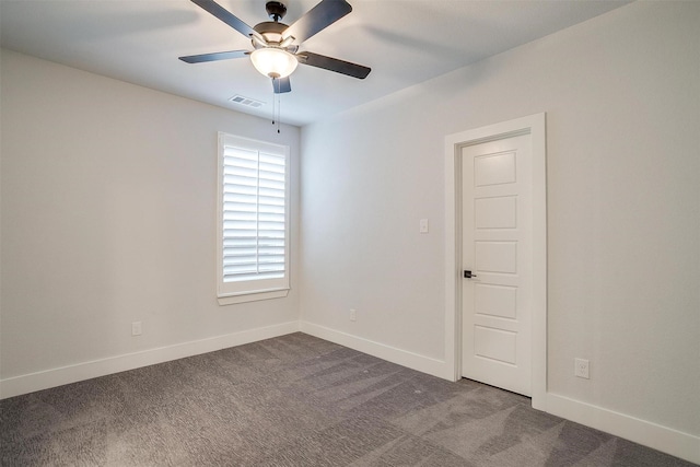 spare room with dark colored carpet, visible vents, baseboards, and ceiling fan