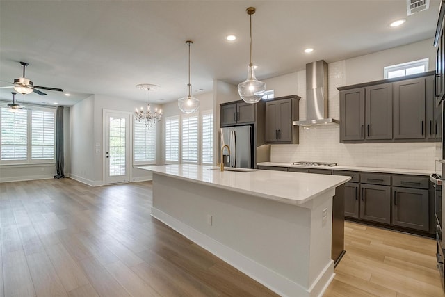 kitchen with baseboards, wall chimney range hood, light countertops, visible vents, and stainless steel appliances