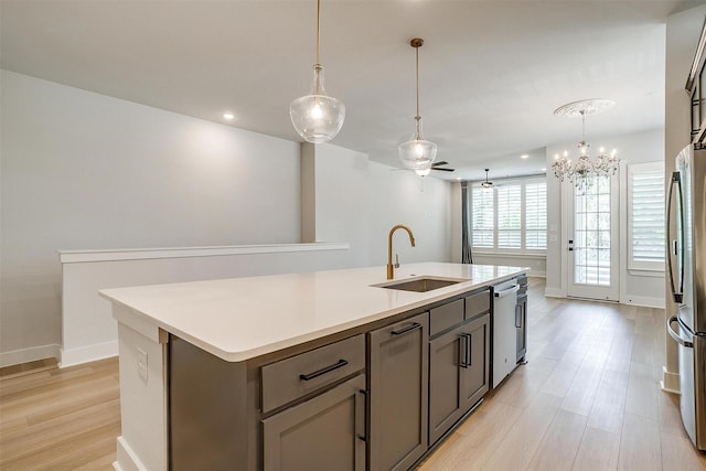 kitchen with stainless steel appliances, an island with sink, a sink, and light wood finished floors
