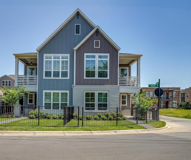 view of front facade with board and batten siding, a front lawn, and a fenced front yard