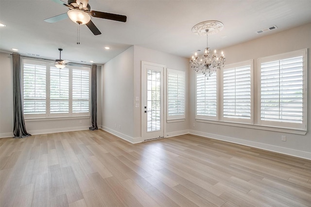 unfurnished dining area featuring visible vents, ceiling fan with notable chandelier, light wood-style floors, and a healthy amount of sunlight