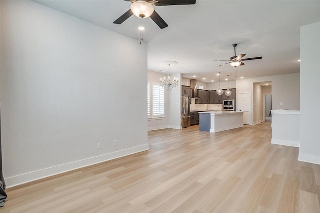 unfurnished living room featuring light wood-style floors, ceiling fan with notable chandelier, baseboards, and recessed lighting