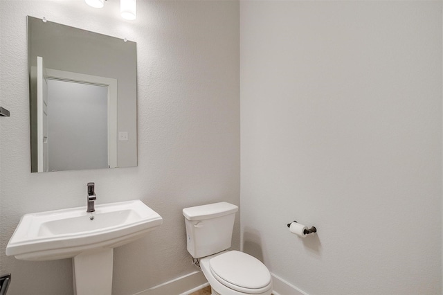 bathroom with baseboards, a sink, and toilet