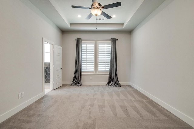 carpeted spare room with visible vents, ceiling fan, a raised ceiling, and baseboards