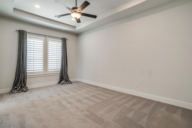 carpeted spare room featuring visible vents, baseboards, ceiling fan, a tray ceiling, and recessed lighting