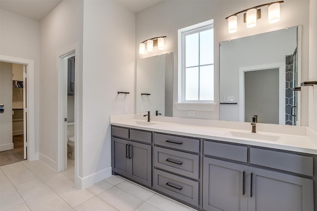 bathroom featuring toilet, tile patterned floors, double vanity, and a sink
