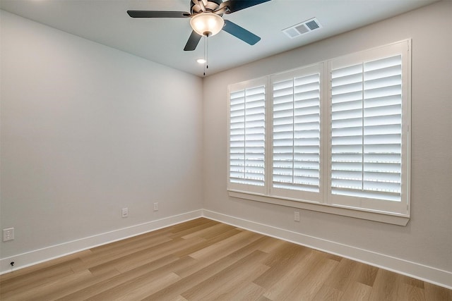 empty room featuring light wood-style flooring, baseboards, a ceiling fan, and visible vents