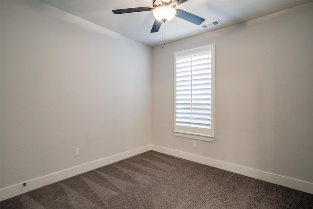 spare room with dark carpet, visible vents, baseboards, and a ceiling fan