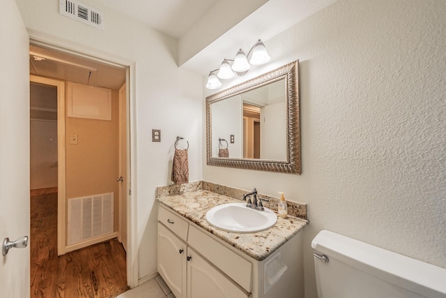 bathroom with visible vents, toilet, vanity, and wood finished floors
