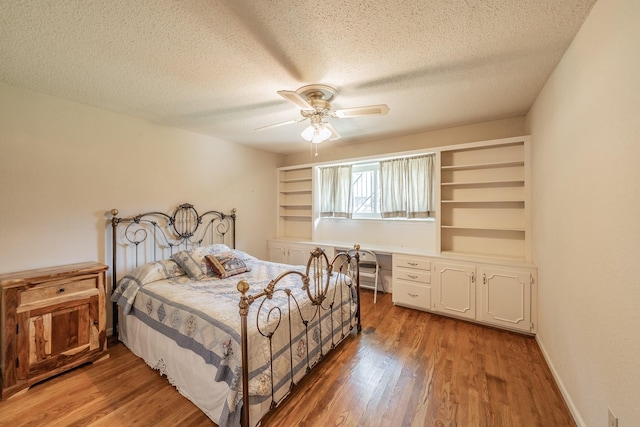 bedroom with light wood-type flooring, built in desk, a textured ceiling, and ceiling fan