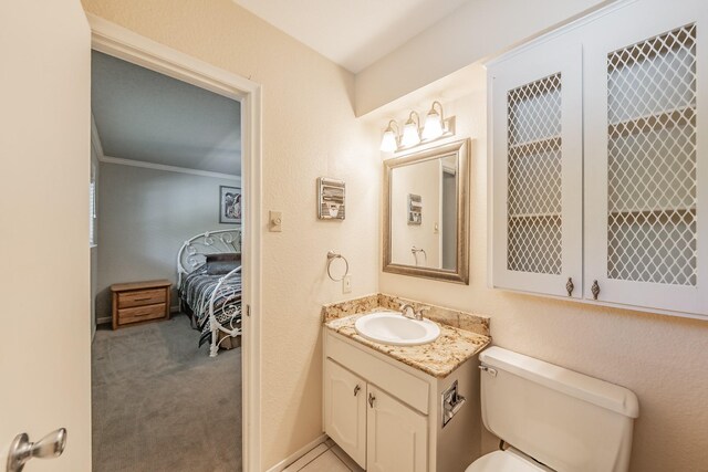 ensuite bathroom with toilet, crown molding, vanity, and ensuite bathroom