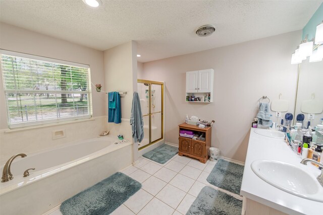 full bath featuring a sink, a textured ceiling, double vanity, tile patterned floors, and a garden tub