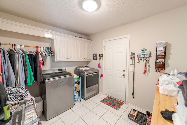 washroom with independent washer and dryer, a textured ceiling, light tile patterned flooring, baseboards, and cabinet space