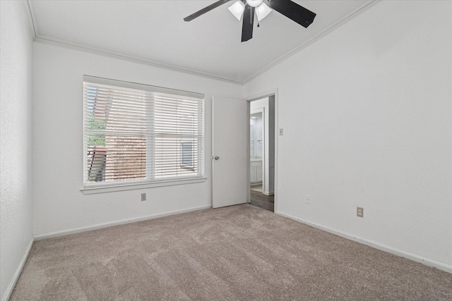 carpeted spare room with lofted ceiling, ceiling fan, ornamental molding, and baseboards