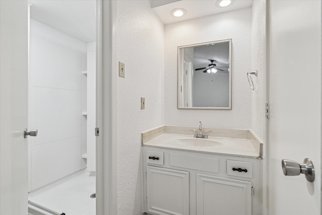bathroom with walk in shower, a textured wall, vanity, and a ceiling fan