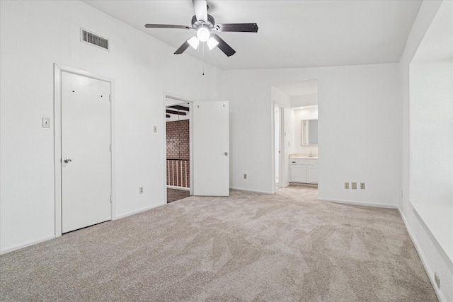 unfurnished bedroom featuring connected bathroom, light colored carpet, vaulted ceiling, baseboards, and visible vents
