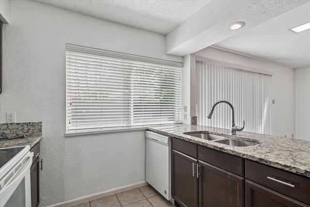 kitchen with a sink, light stone counters, white appliances, a textured ceiling, and dark brown cabinets