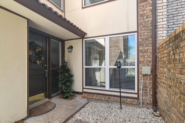 doorway to property featuring brick siding and stucco siding