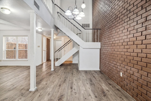 interior space featuring stairs, visible vents, wood finished floors, and brick wall
