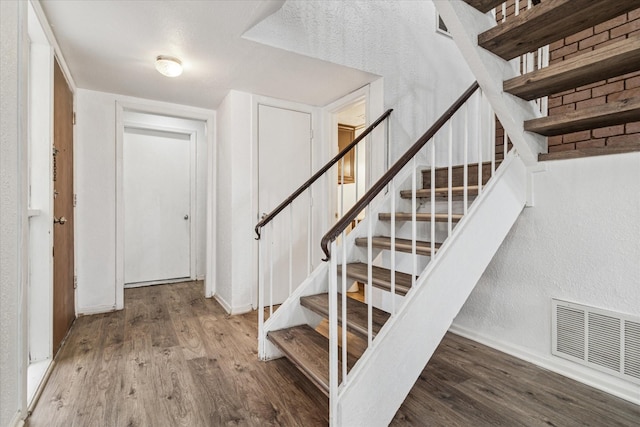 stairway featuring baseboards, visible vents, and wood finished floors