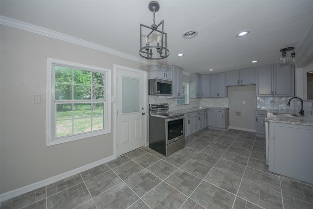 kitchen with a notable chandelier, baseboards, crown molding, appliances with stainless steel finishes, and a sink