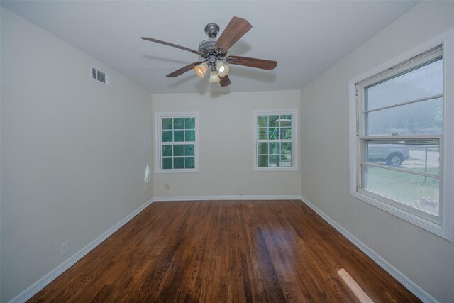 spare room with a ceiling fan, baseboards, dark wood finished floors, and visible vents