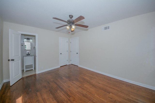 unfurnished bedroom featuring visible vents, baseboards, a ceiling fan, connected bathroom, and wood finished floors