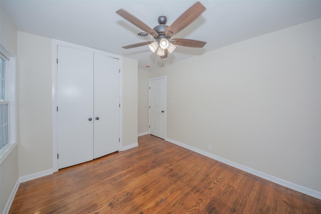 unfurnished bedroom with a closet, baseboards, a ceiling fan, and wood finished floors