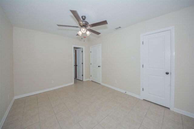 empty room with light tile patterned floors, visible vents, baseboards, and a ceiling fan