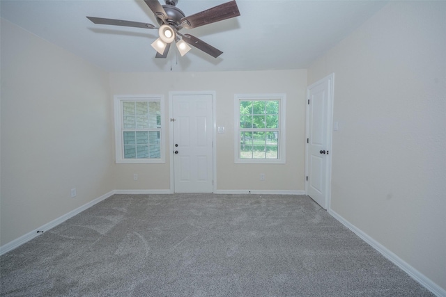 carpeted empty room featuring baseboards and a ceiling fan
