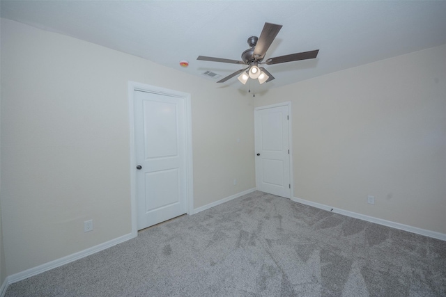 carpeted empty room with visible vents, baseboards, and ceiling fan