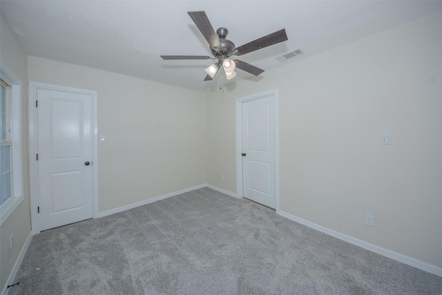 unfurnished room with carpet flooring, visible vents, baseboards, and a ceiling fan