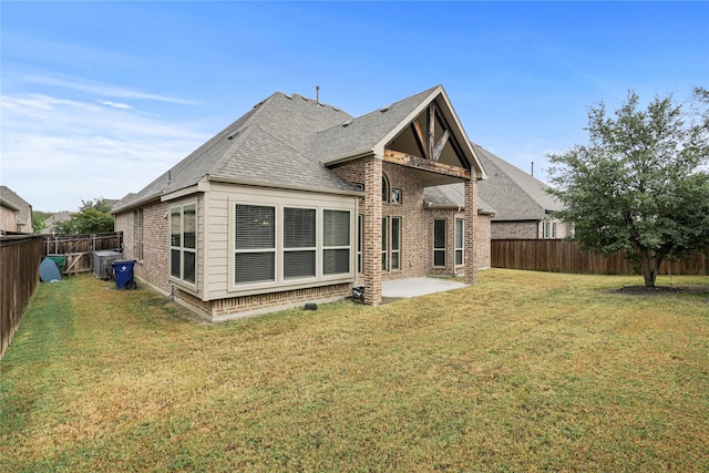rear view of property with a yard, a fenced backyard, a patio, brick siding, and a shingled roof