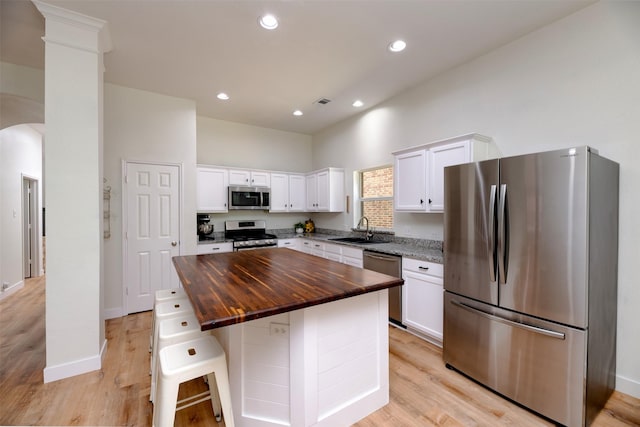 3945 Ringdove Way, Fort Worth, TX 76262 - kitchen featuring appliances with stainless steel finishes, butcher block counters, a sink, arched walkways, and white cabinets