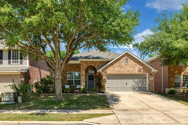 3945 Ringdove Way, Fort Worth, TX 76262 - traditional-style house with a garage, driveway, a front yard, brick siding, and central air condition unit